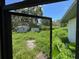 Captured through a screen, the backyard showcases a shed amidst lush greenery, awaiting landscaping to highlight its potential at 34767 Evergreen Way, Ridge Manor, FL 33523