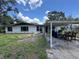 Modest single story home with white siding, a carport, and a lawn needing maintenance at 34767 Evergreen Way, Ridge Manor, FL 33523
