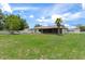 Expansive backyard featuring a screened-in lanai, lush lawn, and mature palm tree for outdoor living and entertainment at 3498 Plaza Ave, Spring Hill, FL 34608