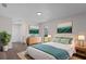 This primary bedroom features wood floors, a bright window, and coastal decor accents at 3498 Plaza Ave, Spring Hill, FL 34608