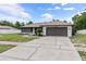 View of the well-maintained single-story home with a brown roof, a front lawn and paved driveway at 3498 Plaza Ave, Spring Hill, FL 34608