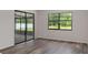 Bright living room features wood-look flooring, a sliding glass door, and a window providing plenty of natural light at 3498 Plaza Ave, Spring Hill, FL 34608
