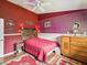 This bedroom features patterned wallpaper, red walls and carpet, and a wooden dresser and headboard at 489 Tournament Dr, Spring Hill, FL 34608