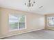 Neutral living room with fresh gray carpet, chandelier, and a window offering natural light at 5048 Teather St, Spring Hill, FL 34608