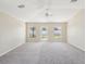 Light-filled living room featuring fresh neutral paint, carpet, a ceiling fan, and an exterior door at 5048 Teather St, Spring Hill, FL 34608