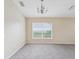 Neutral living room with fresh gray carpet, chandelier, and a window offering natural light at 5048 Teather St, Spring Hill, FL 34608