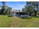 Backyard view featuring the home's screened-in porch and expansive lawn at 5215 Azalea Cir, Dade City, FL 33523