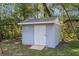 Exterior of a blue storage shed surrounded by lush greenery and mature trees at 5215 Azalea Cir, Dade City, FL 33523