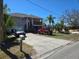Beige two-story home with a front-facing garage, wooden staircase to the porch, and a spacious concrete driveway at 5420 Bay Blvd, Port Richey, FL 34668