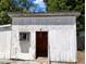 Exterior view of small, one-story white shed with wood paneling, a door, and a single window at 5748 Montana Ave, New Port Richey, FL 34652