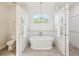 Bright main bathroom features soaking tub, subway tile, gray tile floor, and chandelier at 5903 Cachette De Riviera Ct, New Port Richey, FL 34655