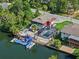 Aerial view of a waterfront home featuring a screened pool, boat dock, landscaped yard, and access to waterways at 6241 Colony Cir, Weeki Wachee, FL 34607