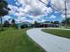 Beautiful curb appeal with a sprawling driveway, lush green lawn, and vibrant landscaping surrounding this well-maintained home at 6737 Clark St, Hudson, FL 34667