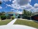 Charming single-story home with a well-manicured lawn and tropical landscaping, enhanced by bright blue skies and fluffy clouds at 6737 Clark St, Hudson, FL 34667
