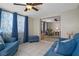 Cozy living room featuring tile floors, ceiling fan, and comfortable blue sofas and chairs at 6930 El Camino Paloma St, Port Richey, FL 34668