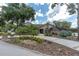 Beautifully landscaped home with lush greenery, circular driveway, and a welcoming entrance at 6936 River Rd, New Port Richey, FL 34652