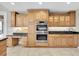 Gourmet kitchen showcases dual ovens, custom wood cabinetry, granite countertops, and tile flooring at 6936 River Rd, New Port Richey, FL 34652