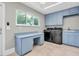 Bright laundry room with blue cabinetry, modern washer/dryer, and large window at 6936 River Rd, New Port Richey, FL 34652