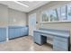Bright laundry room featuring tile flooring, blue cabinetry, workspace, and exterior door at 6936 River Rd, New Port Richey, FL 34652