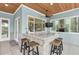 Screened porch wet bar with granite countertop, wooden stools, and ceiling fan at 6936 River Rd, New Port Richey, FL 34652