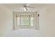 Bright, spacious room featuring neutral carpet, bay window with blinds, and a ceiling fan at 7328 Blue Skies Dr, Spring Hill, FL 34606