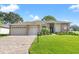 Charming single-story home features a well-manicured lawn, brick accents, and a spacious driveway leading to the garage at 7328 Blue Skies Dr, Spring Hill, FL 34606