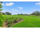 Expansive green lawn with garden beds and golf course scenery, offering a picturesque setting at 7328 Blue Skies Dr, Spring Hill, FL 34606