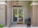 Cozy porch featuring glass front doors, brick pillars, and a comfortable bench with a welcoming mat at 7445 Nature Walk Dr, Spring Hill, FL 34606