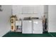 Laundry room with washer, dryer, utility sink, storage cabinets, and green carpet at 7445 Nature Walk Dr, Spring Hill, FL 34606