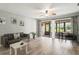 Bright living room with wood-look floors, a comfortable sofa, and sliding glass doors leading to the patio at 7715 Radcliffe Cir, Port Richey, FL 34668