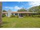 Expansive backyard featuring lush greenery, a covered patio, and mature trees at 8143 Channel Dr, Port Richey, FL 34668