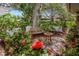 Outdoor patio featuring a metal table, a metal bench, beautiful flowers, and a large shady tree at 8143 Channel Dr, Port Richey, FL 34668