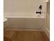 Close up of the bathtub showcasing modern fixtures, subway tile and wood flooring at 8209 Golf Club Ct, Hudson, FL 34667