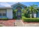 Inviting front entrance with arched doorway, mature landscaping, and a charming statue, exuding elegance at 8540 Caitlin Ct, Hudson, FL 34667