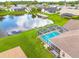 Aerial view of a home with a screened pool overlooking a serene pond and neighboring houses at 8811 Napa Loop, New Port Richey, FL 34653