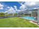 Lush backyard featuring a pool and screened enclosure, perfect for outdoor enjoyment at 8811 Napa Loop, New Port Richey, FL 34653