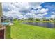 Expansive backyard with lush lawn, screened-in pool, and scenic pond views on a sunny day at 8811 Napa Loop, New Port Richey, FL 34653