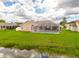 Aerial view of backyard featuring a screened pool, waterfront views, and well-kept lawn, with blue skies at 8811 Napa Loop, New Port Richey, FL 34653