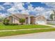 Well-maintained single-story home with a lush lawn, palm trees, and white brick accents on a sunny day at 8811 Napa Loop, New Port Richey, FL 34653