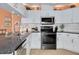 Modern kitchen featuring white cabinets, stainless steel appliances, and granite countertops at 8811 Napa Loop, New Port Richey, FL 34653