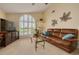 Warm living room featuring a large arched window, comfortable leather sofa, and stylish decor at 8811 Napa Loop, New Port Richey, FL 34653
