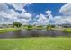 Picturesque pond view surrounded by well-maintained lawns and neighboring homes under a bright, cloudy sky at 8811 Napa Loop, New Port Richey, FL 34653