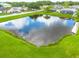 High angle view of a neighborhood pond with clear sky reflections, surrounded by green lawns and houses at 8811 Napa Loop, New Port Richey, FL 34653