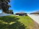 Spacious backyard with lush green grass, white vinyl fence, and covered patio area at 8855 Prairie Creek Dr, New Port Richey, FL 34655