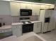 Classic kitchen features white cabinets, black appliances, and tile backsplash at 9168 Southern Comfort Ct, Weeki Wachee, FL 34613