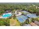 Aerial view showcasing the community pool and tennis courts surrounded by a lush, green landscape at 9420 Georgian Park Ln # 106, Tampa, FL 33626