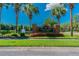 Community entrance featuring a brick sign, landscaping, and a glimpse of a lake and fountain at 9420 Georgian Park Ln # 106, Tampa, FL 33626