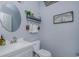Stylish half bathroom featuring a round mirror, shelf, and decorative elements at 9420 Georgian Park Ln # 106, Tampa, FL 33626