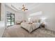 Bright primary bedroom featuring tray ceilings, ceiling fan, sitting area, and pool views at 9829 Sorbonne Loop, Seffner, FL 33584