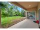 View from the covered back porch with sliding glass door access, overlooking a green yard with tropical landscaping at 10925 Oyster Bay Cir, New Port Richey, FL 34654